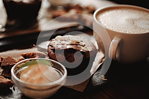 Close up food image of cup of coffee and dessert on the wooden table background in cafe. Trend warm toning. Photo with a small dep