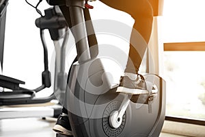 Close up foot biking in gym, exercising legs doing cardio workout cycling bikes