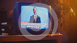 Close Up Footage of a Dated TV Set Screen with Breaking News Report. Handsome Middle Aged Anchorman