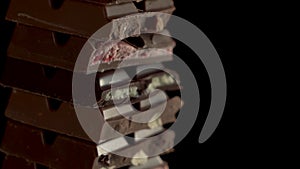 Close up footage tower of pieces different chunks of chocolates rotate on a black background. Strawberry, mascarpone