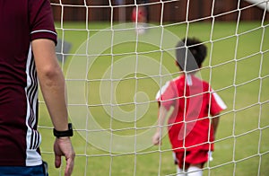 Close-up of football goal net, seeing a young soccer goalie goalkeeper during the match.