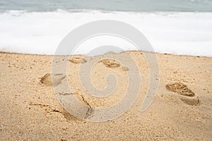 Close up on footprints on sand at beach seashore