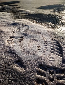 shoe marks close-up on the snow in front of the ice on the lake