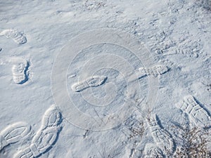 Close up of footprints on white snow. Human footmarks of unknown people on ground with precipitation in winter season.