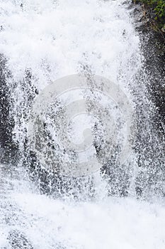 Close up of Forceful Flow of Water with Sprinkling of White Drops