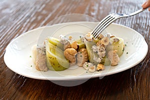 Close-up of a fork poking into a plate of leek salad with meuniere sauce, gourmet style