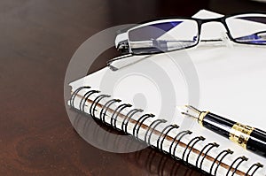 Close up of fountain pen on notebooks with glasses