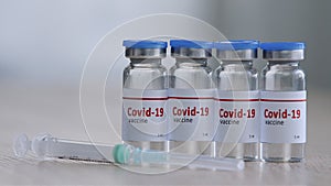 Close-up of four glass bottles with vaccine drug against covid-19 virus remedy for epidemic of coronavirus immunization