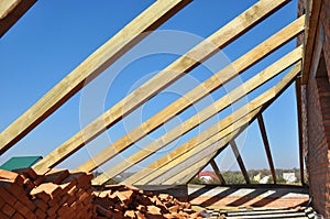 A close-up on framing the rooftop of a brick house with trusses, roof beams, roof eaves, braces and planks in roofing construction