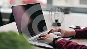 Close up of freelancer's hands typing code on laptop keyboard. Camera slides around developer's figers writing