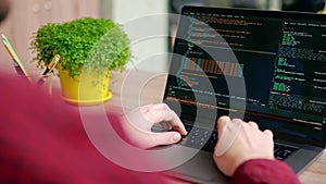 Close up of freelancer's hands typing code on laptop keyboard. Camera slides around developer's figers writing