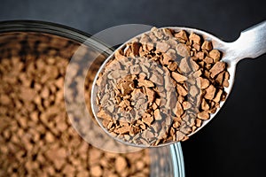 Close up of Freeze Dried Instant Coffee on Tea Spoon with Glass Coffee Cup Background