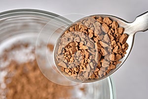 Close up, Freeze Dried Instant Coffee on Tea Spoon with Glass Coffee Cup Background