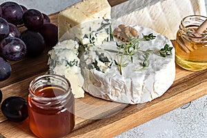 Close up of french cheeses assortment. Delicatessen camembert, brie, and roquefort on the wooden cutting board.