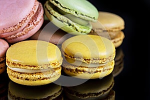 Close-up of French dessert for coffee. Multicolored macarons on black background