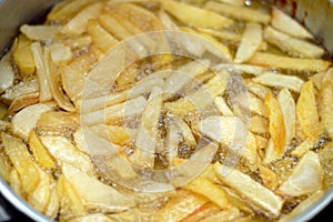 Close-up of French fries potatoes frying in boiling hot oil in a deep fryer at home. French fries, Junk food concept, home made