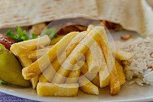 Close up of french fries, rice and shawarma on plate