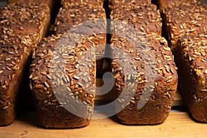 Close-up fresh brown loaves of rye bread in the form of bricks with sunflower seeds on a crust. Lie on a wooden rack