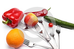 Close up of fresh cherry tomato, red peppers, cucumber, apple and orange fruits on forks on white background. Healthy eating and