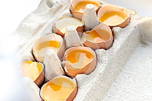 Close-up of fresh chicken eggs yolks in a shell on cardboard tray.