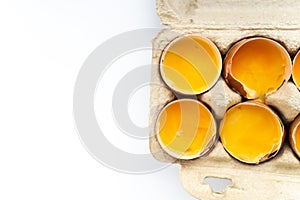 Close-up of fresh chicken eggs yolks in a shell on cardboard tray. Top view. Flat lay