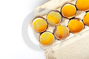 Close-up of fresh chicken eggs yolks in a shell on cardboard tray. Top view. Flat lay