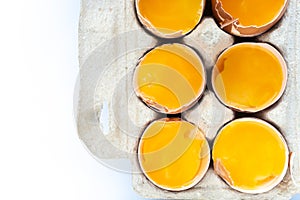 Close-up of fresh chicken eggs yolks in a shell on cardboard tray. Top view. Flat lay