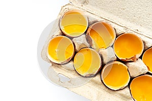 Close-up of fresh chicken eggs yolks in a shell on cardboard tray. Top view. Flat lay