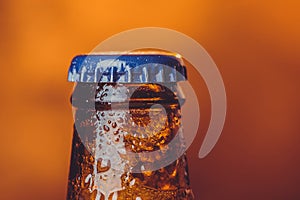 close-up of fresh cold beer ale single bottle with drops and stopper on warm background