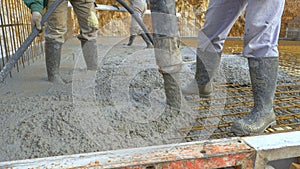 CLOSE UP: Fresh concrete flows out of a wide hose as contractors pour a slab.