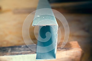 Close-up of a fresh cut of a metal U profile against a blurred background. Sharp edges of the metal profile after the grinder