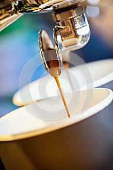 Close-up fresh espresso pours in disposable cup, Italian espresso machine. Coffee culture, professional coffee making