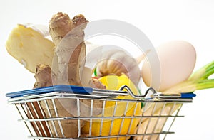 Close-up fresh food in a supermarket basket with ginger, lemon and eggs with fresh herbs