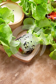 Close up of fresh handmade vegan rice paper spring rolls with raw vegetables on wooden plate with dipping sauce on grunge brown