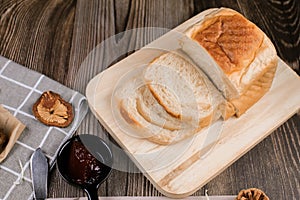 Close up fresh homemade loafs bread and sliced bread on cutting board with jam strawberry on wooden background