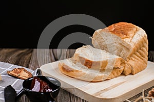 Close up fresh homemade loafs bread and sliced bread on cutting board with jam strawberry on wooden background