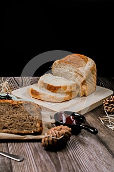 Close up fresh homemade loafs bread and sliced bread on cutting board with jam strawberry on wooden background.Healthy Diet.Prepar