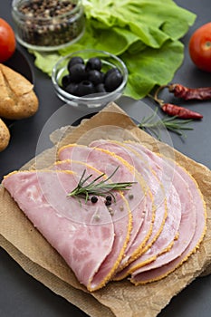 Close up fresh hum meat for sandwiches, dark board with vegetables on background