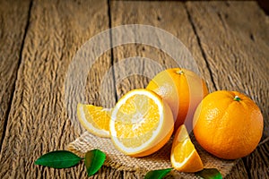 Close-up of Fresh oranges, half-cut fruit, slice with green leaves on an old wood vintage table.