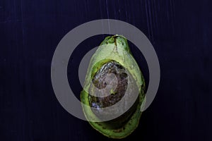 Close up fresh organic avocado halves on old black table background. Healthy food concept