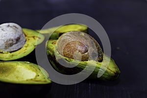 Close up fresh organic avocado halves on old black table background. Healthy food concept