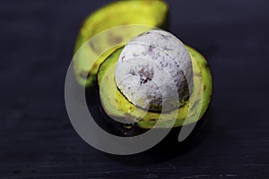 Close up fresh organic avocado halves on old black table background. Healthy food concept