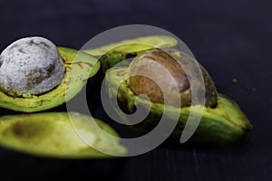 Close up fresh organic avocado halves on old black table background. Healthy food concept