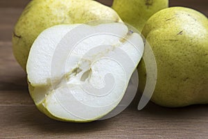 Whole and sliced green pears on wooden board