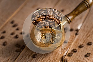 Close up of fresh roasted coffe beans in  cezve traditional turkish coffee pot on wooden table