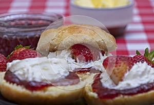 Close up of fresh scones topped with strawberry jam,cream