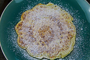 Close up of fresh waffle coated with icing sugar on blue china plate