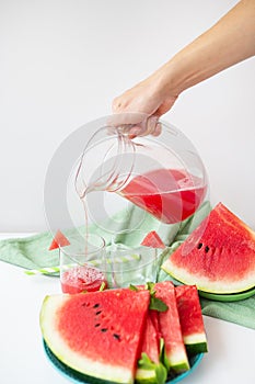 Close-up of fresh watermelon juice or smoothie in glasses with watermelon slices on a white table. A refreshing summer drink is