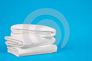 Close up fresh white folded linens on a blue background. Room service maid cleaning hotel room