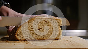 Close Up of freshly baked bread being sliced with a bread knife in Slow Motion.